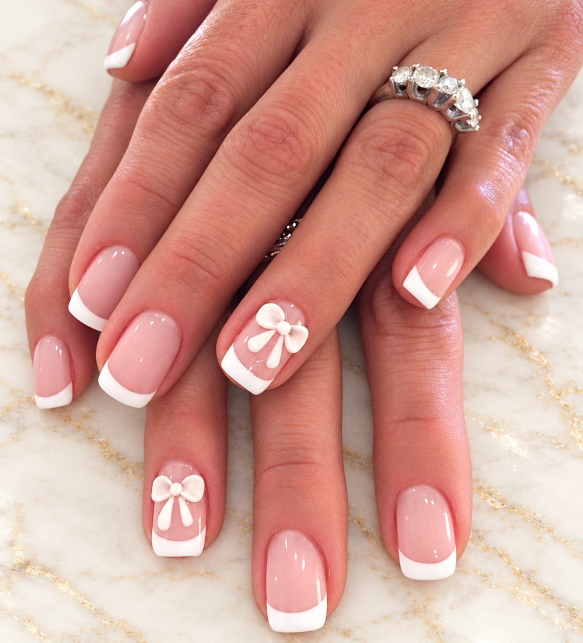 French manicure with bow nail art on an ivory marble background